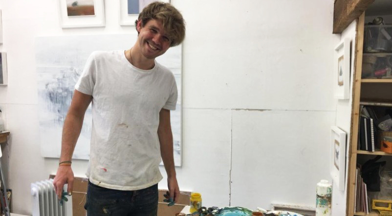Toby O'Brien, a young man with blonde hair and a big smile with paint on his hands